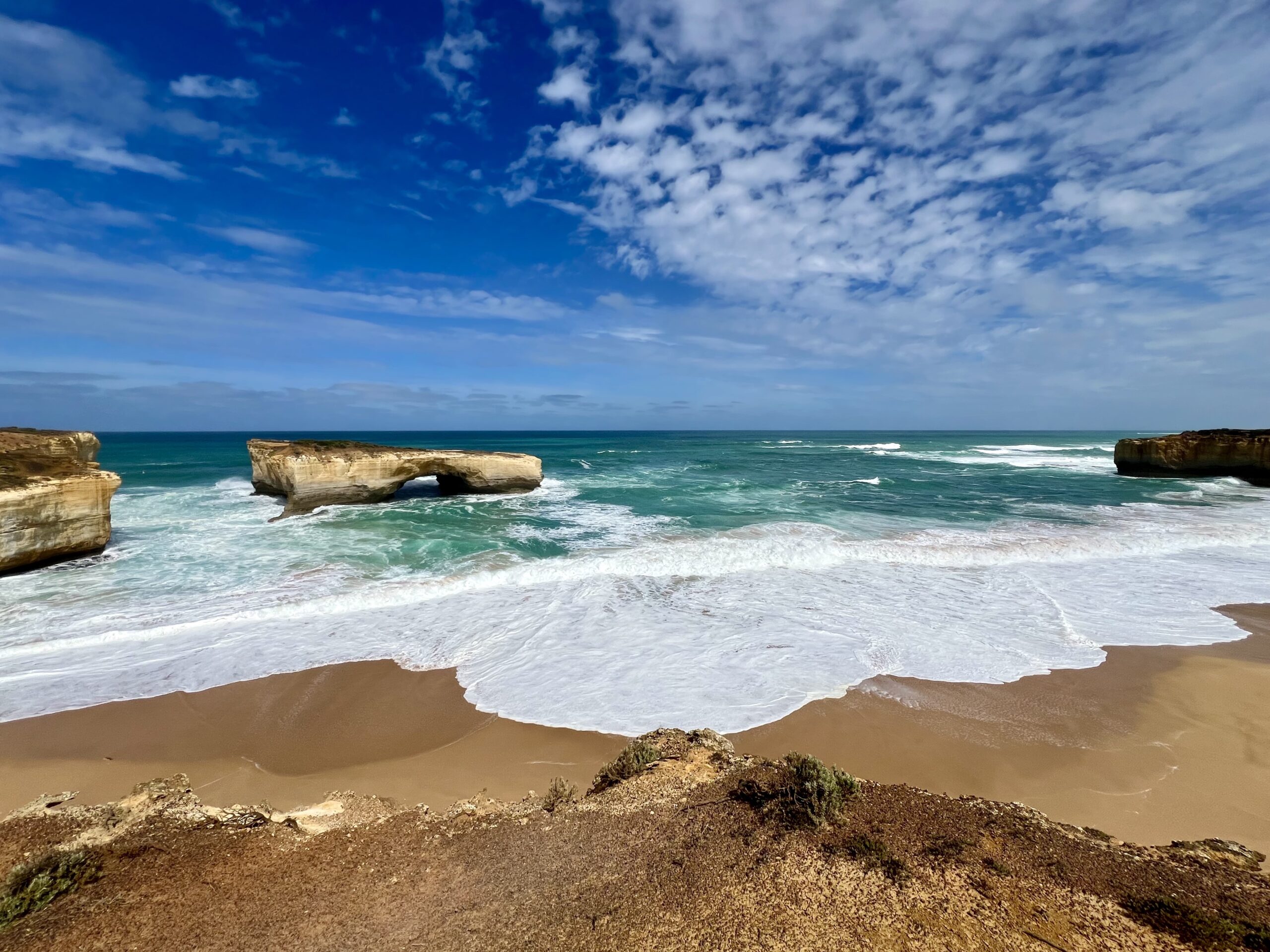 Spiaggia australiana con onde bianche, rocce e cielo azzurro