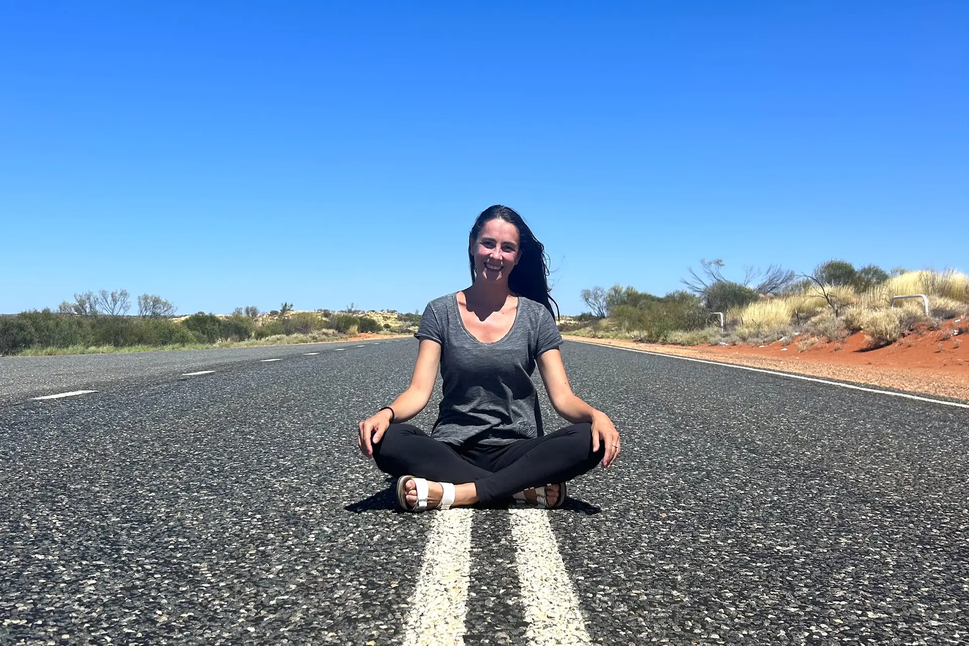 Viaggiatrice seduta su una strada nel paesaggio australiano