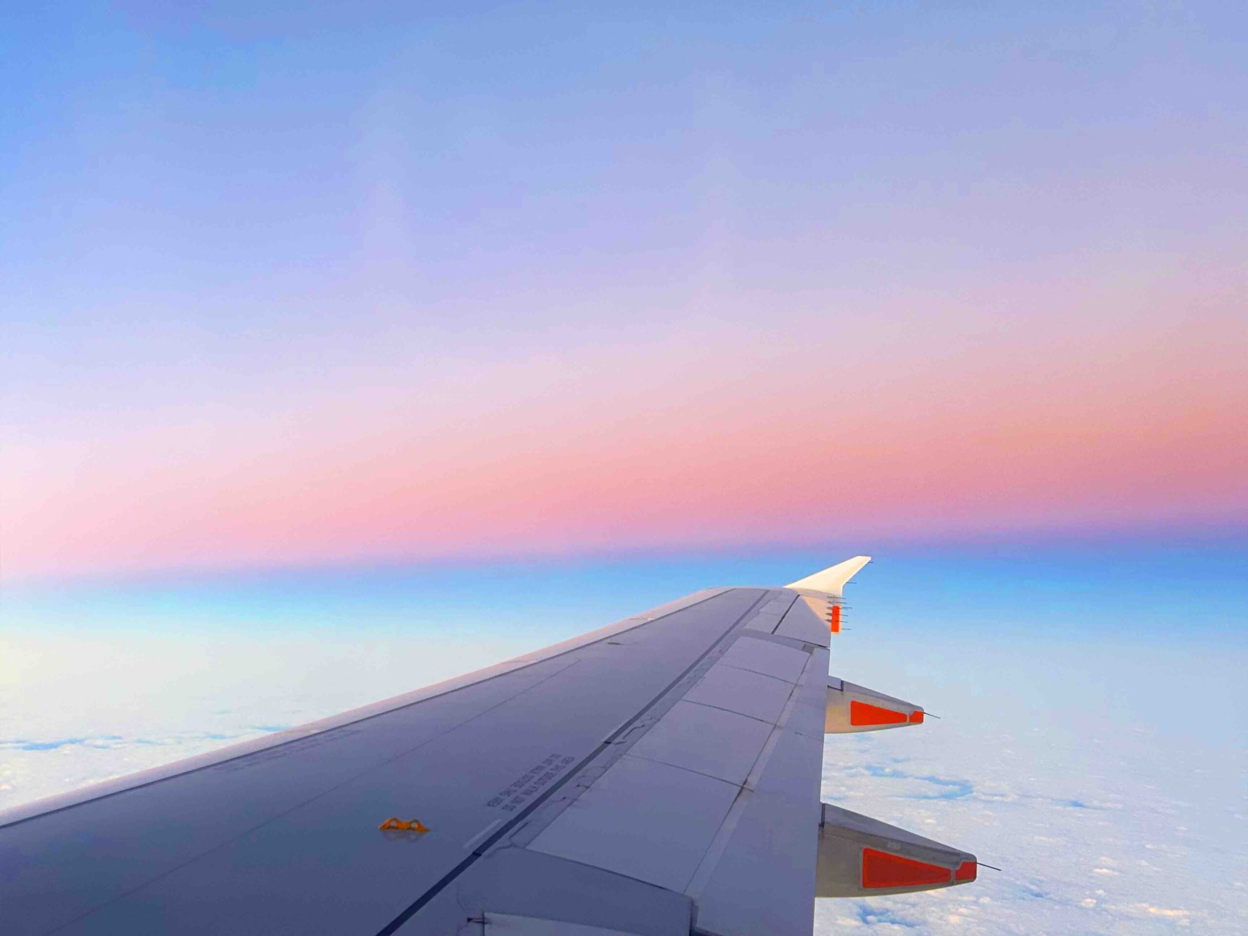 Ala di un aereo sopra un cielo rosa e azzurro